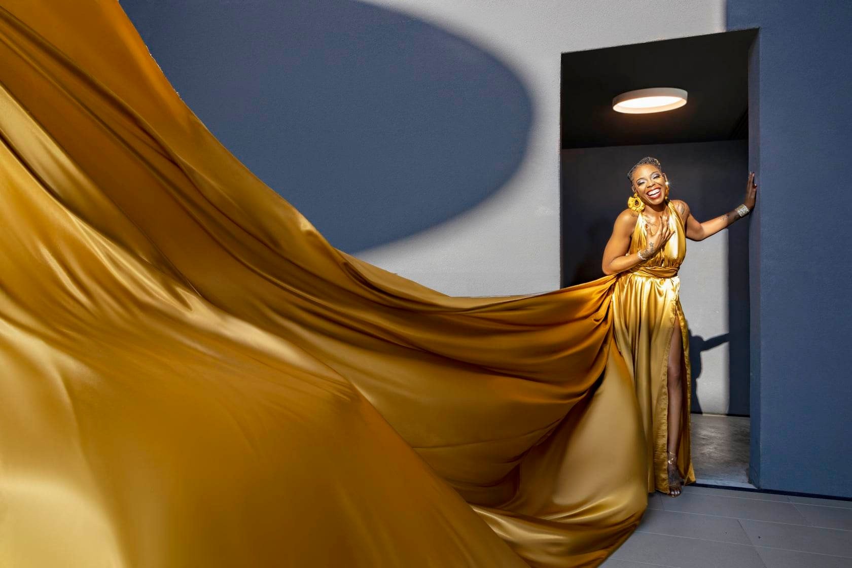 Flying dress — gold gown, blue architectural backdrop