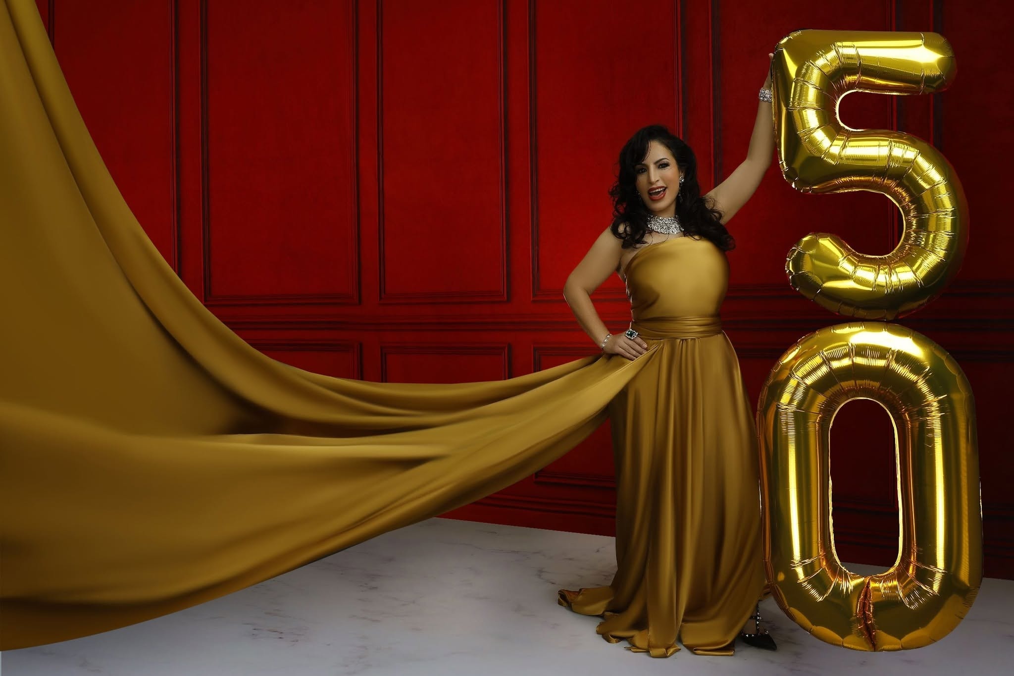 Flying dress — gold gown, red backdrop, 50 balloons