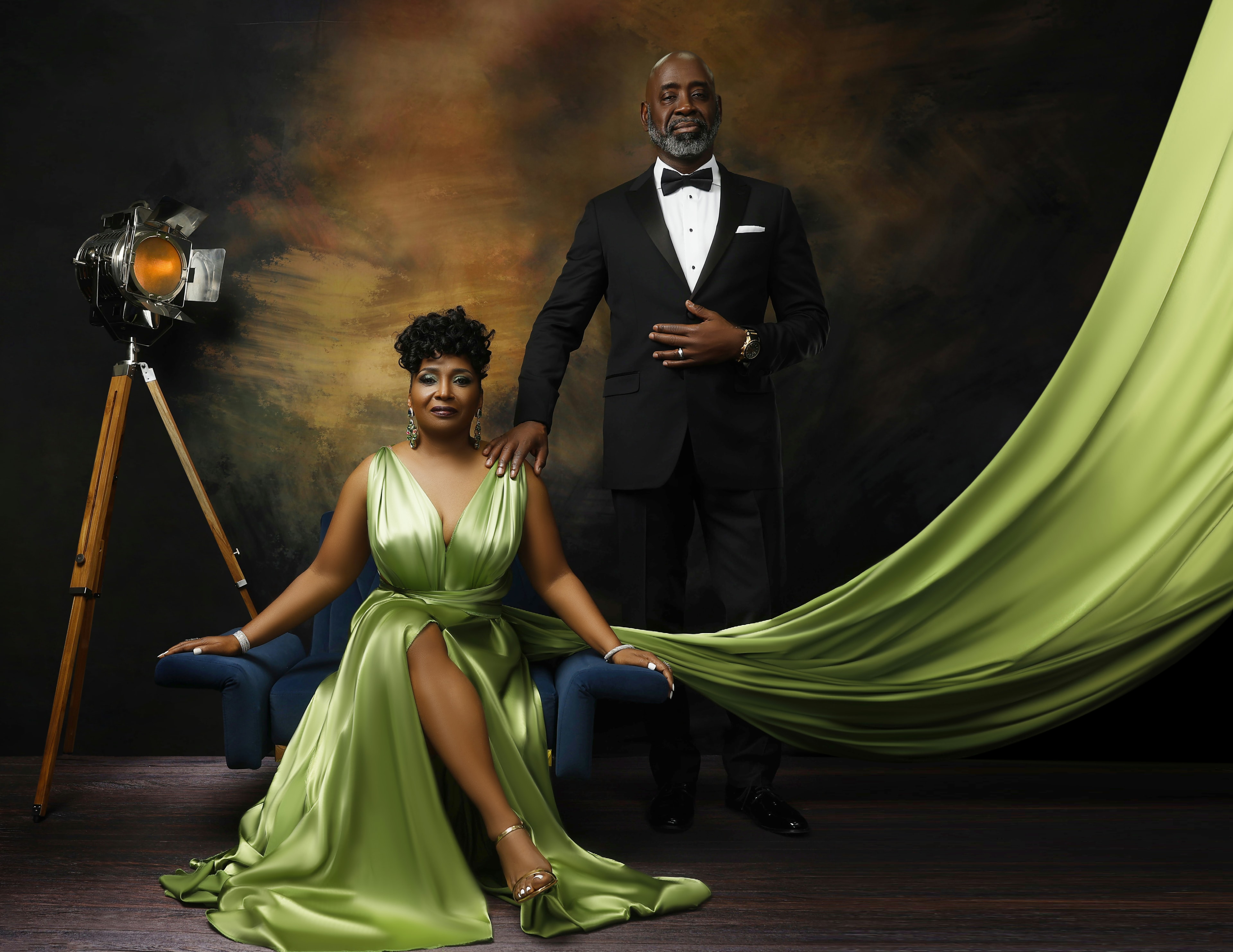 Nannette Ray — green gown seated, dark studio backdrop, couple portrait